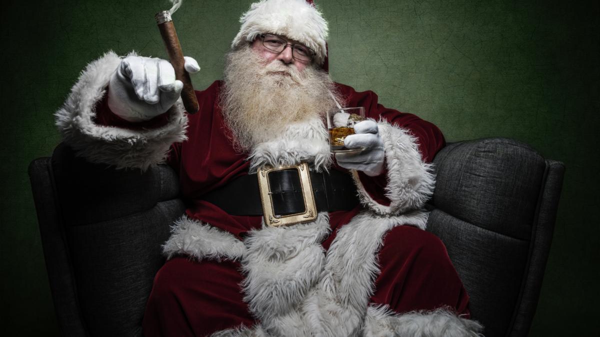 Image of Santa holding a drink and a cigar sitting in a chair