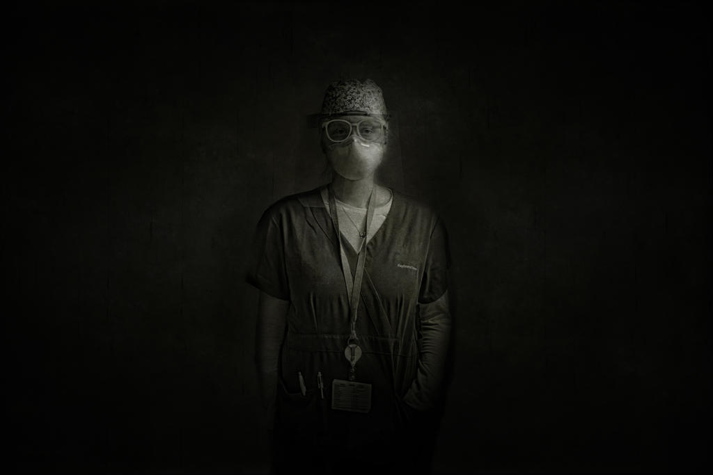 A woman wearing a mask and scrubs.