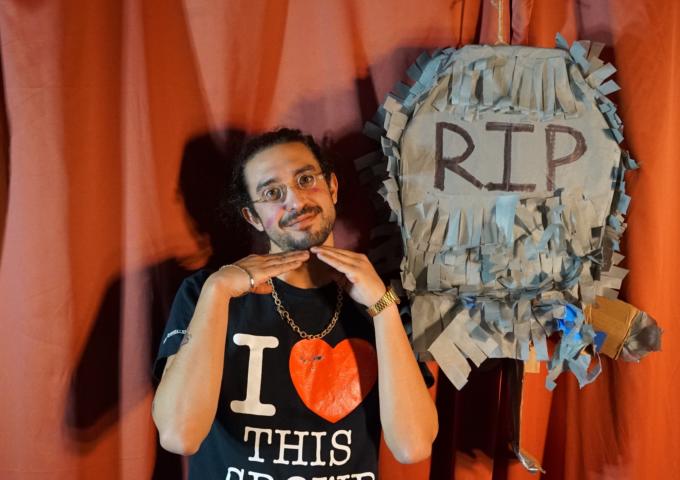 Comedian Dave Wasserman poses like an adorable child in front of a paper machete gravestone.