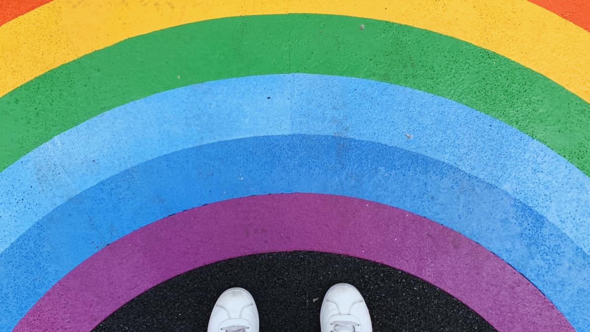Shoes and legs next to a rainbow drawing on the floor