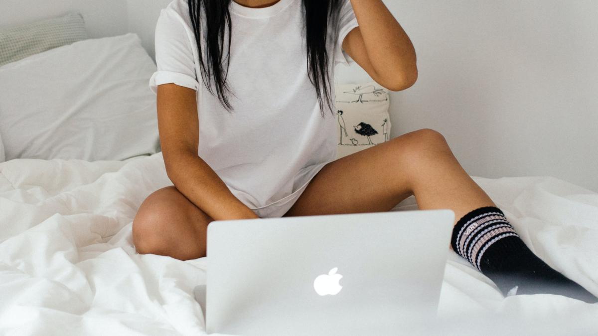 A woman sitting on a bed with a laptop