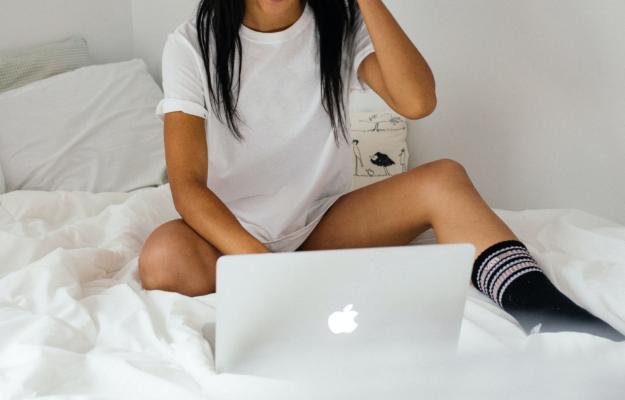 A woman sitting on a bed with a laptop