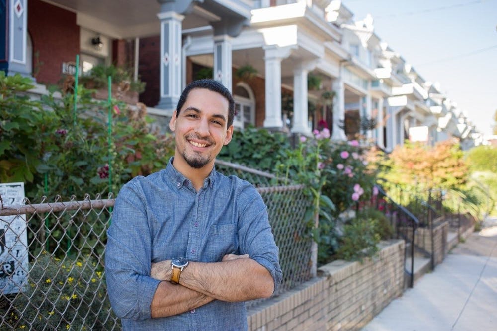 Paul Prescod standing in his West Philadelphia neighborhood smiling with his sleeves rolled up.