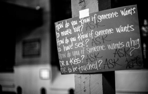 A handwritten placard that reads, "How do you know if someone wants to make out? Ask. How do you know if someone wants to have sex? Ask. How do you know if someone wants to hug or a kiss or to be touched? Ask, ask, ask."
