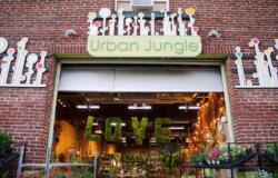 The facade of Urban Jungle on Passyunk Avenue, a brick garage with a big opening and lots of lush plants inside.