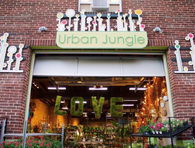 The facade of Urban Jungle on Passyunk Avenue, a brick garage with a big opening and lots of lush plants inside.