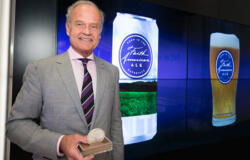 Kelsey Grammer stands in front of screens showing his brewery's latest concotions.