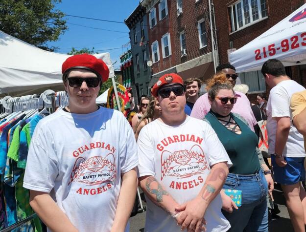 Two men in Guardian Angels shirts, including TJ Cahill, wearing berets at a South Philly community event. They are wearing sunglasses, too, and posing tough.